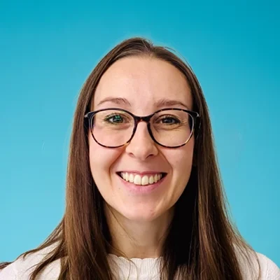 Chiropractic Assistant Laura Smiling In Front Of Blue Wall